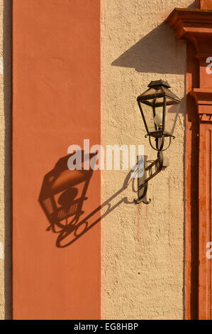 Lanterne avec son ombre sur un mur orange, à l'église de Zell am Harmersbach, Allemagne Banque D'Images