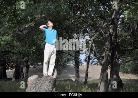 Heureux homme debout sur une souche dans la forêt de chêne Banque D'Images