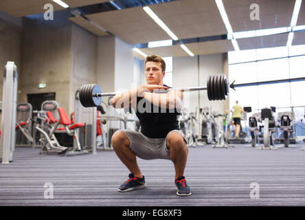 Young man flexing muscles avec barbell in gym Banque D'Images