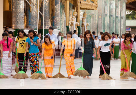 Les jeunes femmes birmanes balayant le sol au coucher du soleil, de la pagode Shwedagon, Yangon, Myanmar ( Birmanie ), l'Asie Banque D'Images