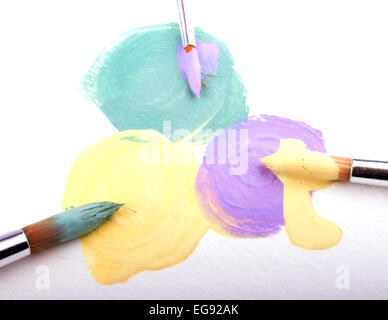 Vert, jaune et lilas des taches de peinture sur papier texturé blanc, avec des brosses avec des couleurs de peinture sur chaque Banque D'Images