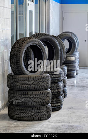Des piles de pneus, avec bande de roulement pour diverses conditions de conduite, à vendre dans un garage automobile Banque D'Images
