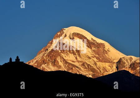 L'église de trinité Gergeti (Tsminda Sameba) qui se profile à l'aube avec le Mont Kazbek en arrière-plan, Caucase, Géorgie Banque D'Images