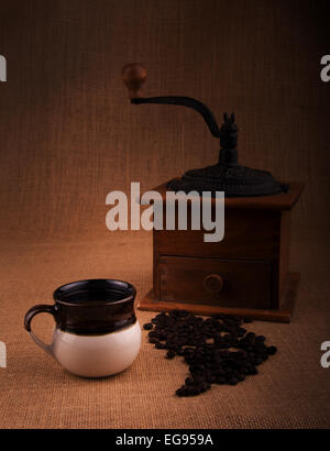 Tasse de café avec des haricots et un vieux moulin sur l'arrière-plan, une image aux teintes chaleureuses avec vignette Banque D'Images