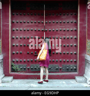 Woman peeking through gate, la Cité Interdite, Pékin, Chine Banque D'Images