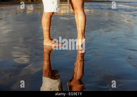 La section basse de jeune couple standing on beach Banque D'Images