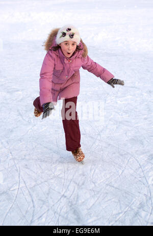 Jolie fille au chapeau et veste rose patinage sur glace un jour d'hiver ensoleillé Banque D'Images