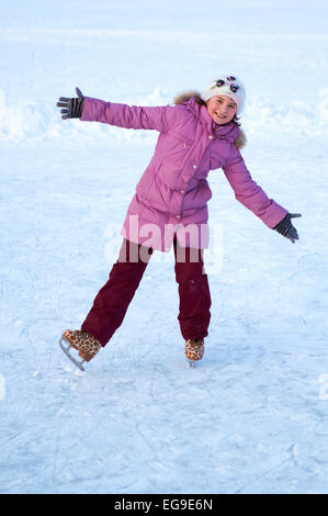 Jolie fille au chapeau et veste rose patinage sur glace un jour d'hiver ensoleillé Banque D'Images