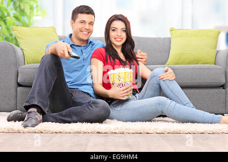 Heureux couple watching TV and eating popcorn at home Banque D'Images