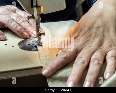 Gros plan du senior woman's hands sciage à façon , frontière avec machine à coudre Banque D'Images