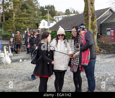 Les touristes à l'aide de mobile smartphone Iphone - selfies autoportraits stick pour prendre des photos et vidéos d'eux-mêmes le lac Windermere Cumbria 20e Février 2015. Bowness Bay .moitié froide à long terme pour des excursions en bateau et les touristes de tous les nationalties Crédit : Gordon Shoosmith/Alamy Live News Banque D'Images