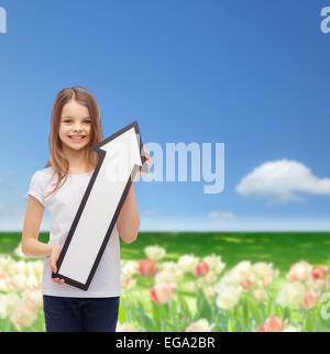 Smiling little girl avec flèche blanche pointant vers le haut Banque D'Images