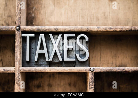 Le mot 'TAXES' écrit en metal vintage type typographique dans un tiroir en bois avec des séparateurs. Banque D'Images