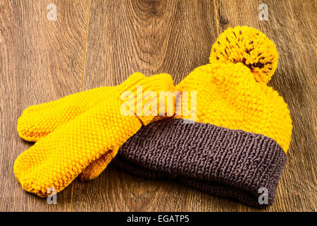 Tricoter des mitaines et chapeau jaune sur fond de bois Banque D'Images