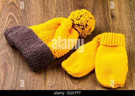 Tricoter des mitaines et chapeau jaune sur fond de bois Banque D'Images