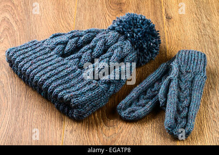 Tricoter des mitaines et chapeau gris sur fond de bois Banque D'Images