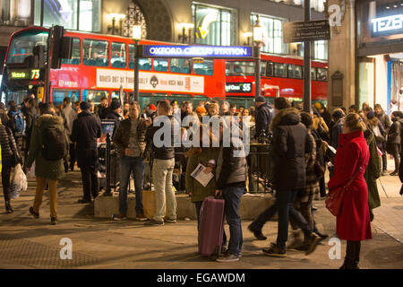 Un couple consulte leur téléphone mobile alors que les navetteurs se démettent Le métro à la station Oxford Street Banque D'Images