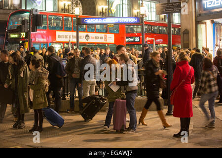 Un couple consulte leur téléphone mobile alors que les navetteurs se démettent Le métro à la station Oxford Street Banque D'Images