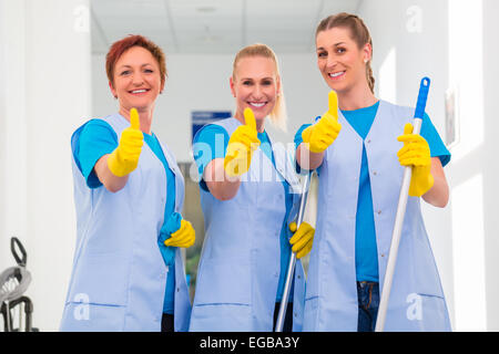 Les femmes de ménage travaillant dans l'équipe montrant Thumbs up sign Banque D'Images