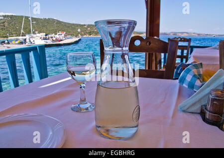 Boire le vin blanc dans une ombre d'une taverne grecque typique par le port Banque D'Images