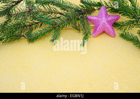 Brillant et Rose star ornament avec branches sur une nappe jaune Banque D'Images