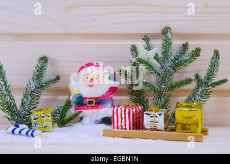 Toy Santa entre sapins et présente sur une surface en bois enneigé Banque D'Images