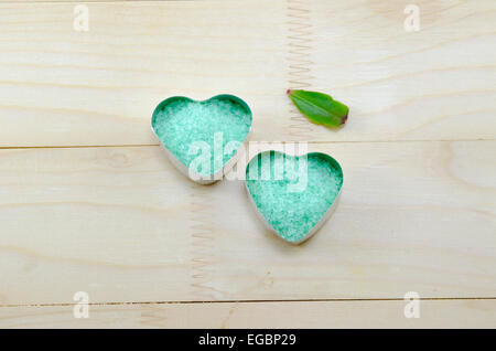 Le sel de mer verte dans une boîte en forme de coeur sur une table en bois avec une feuille verte Banque D'Images