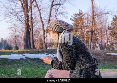 Jeune femme textos de plein air en hiver Banque D'Images