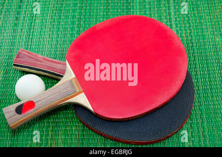 Deux raquettes de tennis de table et une balle de ping-pong sur la surface verte Banque D'Images