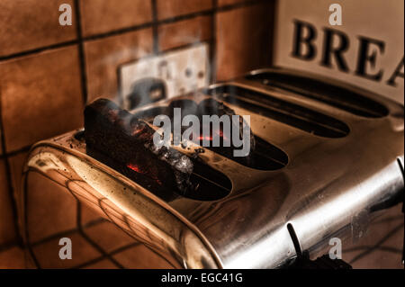 Risque d'incendie fumeurs burning toast oublié dans le grille-pain dans la cuisine prendre feu brûlant et rougeoyant pain carbonisé Banque D'Images