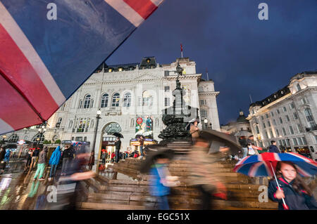 Les gens avec des parasols à Piccadilly Circus, la nuit, Londres, UK Banque D'Images