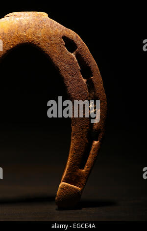 Tourné en couleur d'un fer à cheval rouillé sur un fond sombre. Banque D'Images