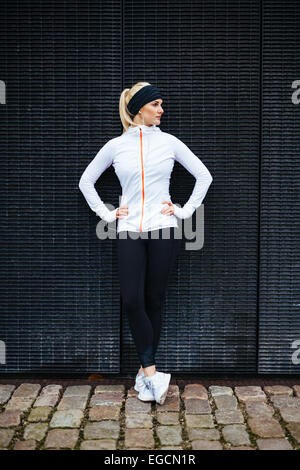 Toute la longueur de balle sporty young woman relaxing après exécution de l'exercice. Athlète féminin se reposant après le jogging dans la ville. Banque D'Images