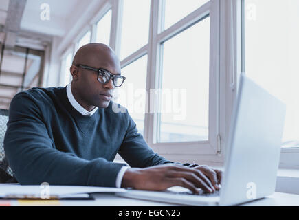 Image de l'african american businessman travaille sur son ordinateur portable. Beau jeune homme à son bureau. Banque D'Images