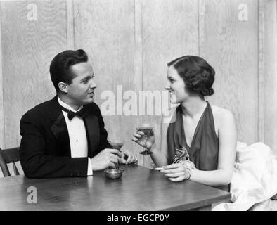 1930 1940 MAN TOASTING CLUB TABLE CIGARETTE HOMME FEMME HOMME FEMME COUPLES SMOKING MARTINI RESTAURANT PARTIE Banque D'Images