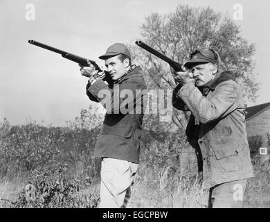 Années 1940 Années 1950 JEUNES HOMMES HAUTS AVEC DES FUSILS DE CHASSE VISANT À PORTER DES VÊTEMENTS DE L'APPAREIL PHOTO & HATS Banque D'Images