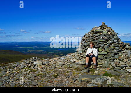 La mise à l'abri derrière le cairn du sommet sur Meall a'Bhuachaille, Aviemore, Highlands écossais. Banque D'Images