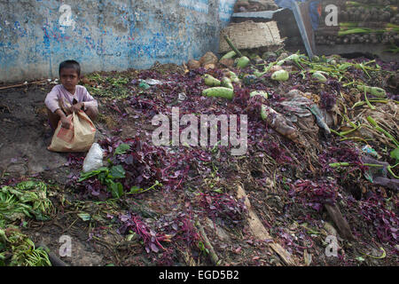 Slum boy Shawqat la collecte de déchets de légumes pourris à Shambazar dans la rive de la rivière Buriganga à les vendre bidonville à Dhaka. Banque D'Images