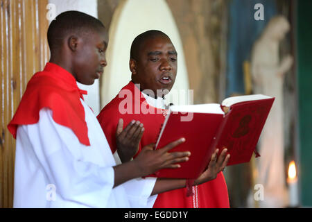 Prêtre lecture de la bible, tenue par un enfant de chœur au cours de la messe du dimanche dans une église catholique romaine à Ndola, Zambie Banque D'Images