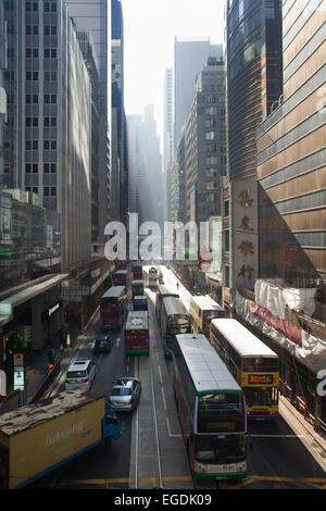 Des Voeux Road et de trafic dans le soleil du matin dans le centre de district. Les bus, trams et voitures amène les gens à travailler tôt le matin. Banque D'Images