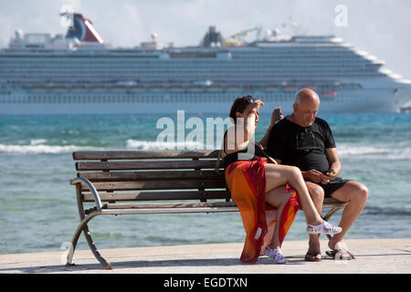Couple sur un banc en face d'un navire de croisière au port, Mahahual, Quintana Roo, Mexique Banque D'Images