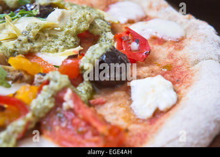 Partie d'une pizza traditionnelle italienne avec artichauts, tomates et olives Banque D'Images