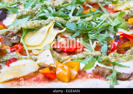 Partie d'une pizza traditionnelle italienne avec artichauts, tomates et olives Banque D'Images