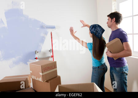 Jeune couple discutant où pour placer des objets sur le mur Banque D'Images