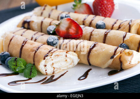 Délicieux crêpes roulées sur une assiette de fruits frais Banque D'Images