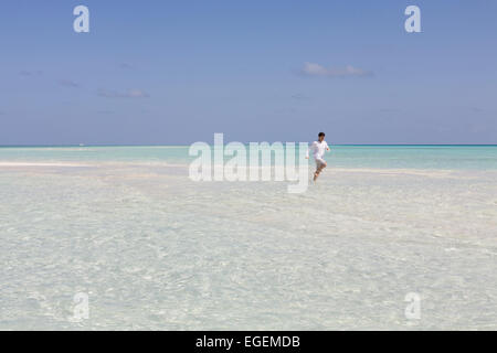 Jeune homme qui court sur de belles vacances à la plage tropicale dans Kuramathi resort Banque D'Images