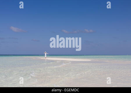 Jeune femme debout le long de la plage de sable blanc déserte entourée par des eaux tropicales aux Maldives Inde près de profiter de la lumière du soleil Banque D'Images