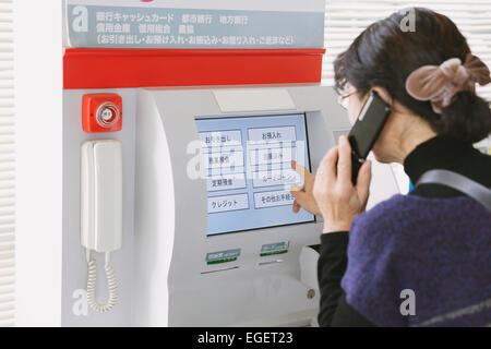 Femme japonaise en utilisant un guichet automatique dans un magasin de proximité Banque D'Images