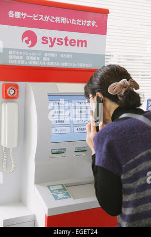 Femme japonaise en utilisant un guichet automatique dans un magasin de proximité Banque D'Images