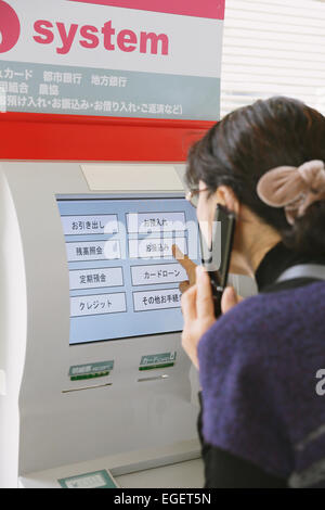 Femme japonaise en utilisant un guichet automatique dans un magasin de proximité Banque D'Images